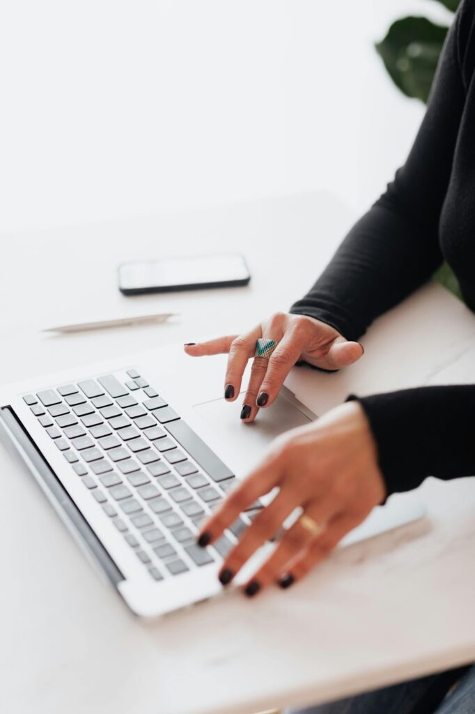 A woman sitting at a desk, typing on a laptop