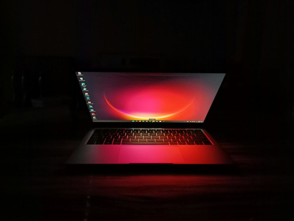 A laptop screen glowing in a dark room, casting light on the surrounding area