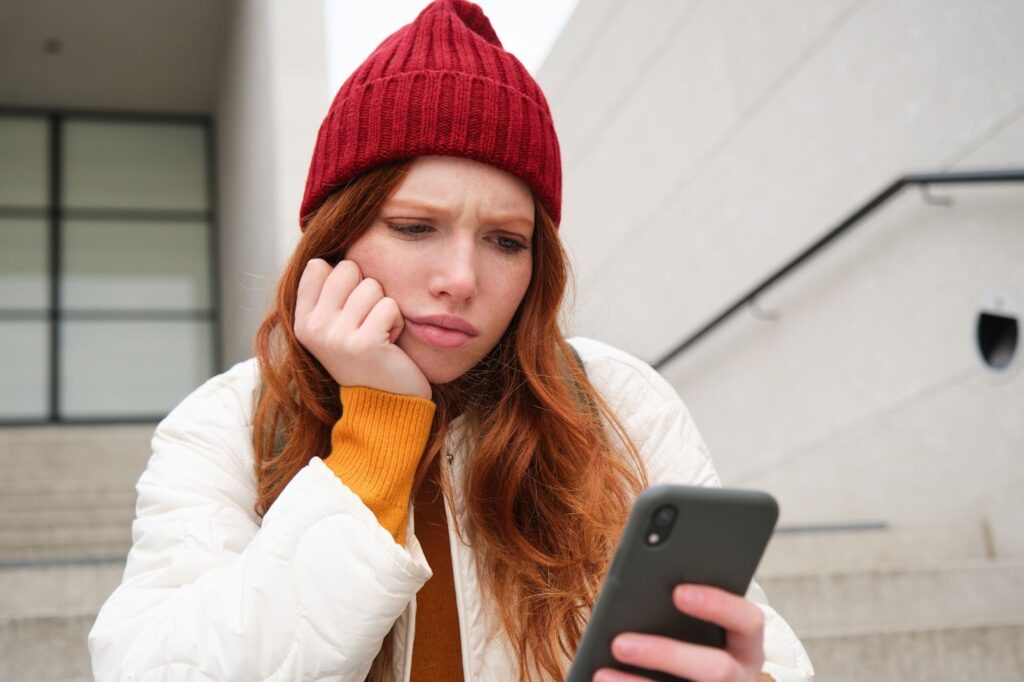 Woman looking at her phone with a curious expression.